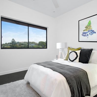 white bedspread on bed near window